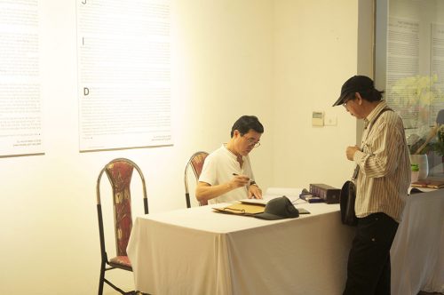 Họa sĩ Đinh Phong ký tặng sách trong cuộc Triển Lãm lần 3 tại Hà Nội tháng 5 năm 2022